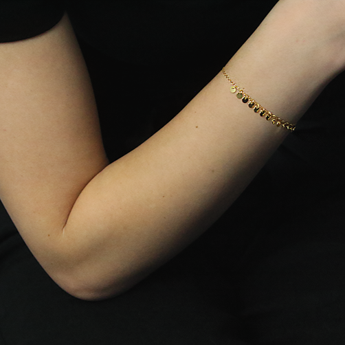 18kt Yellow Gold Plated String of Charms Bracelet worn by a woman