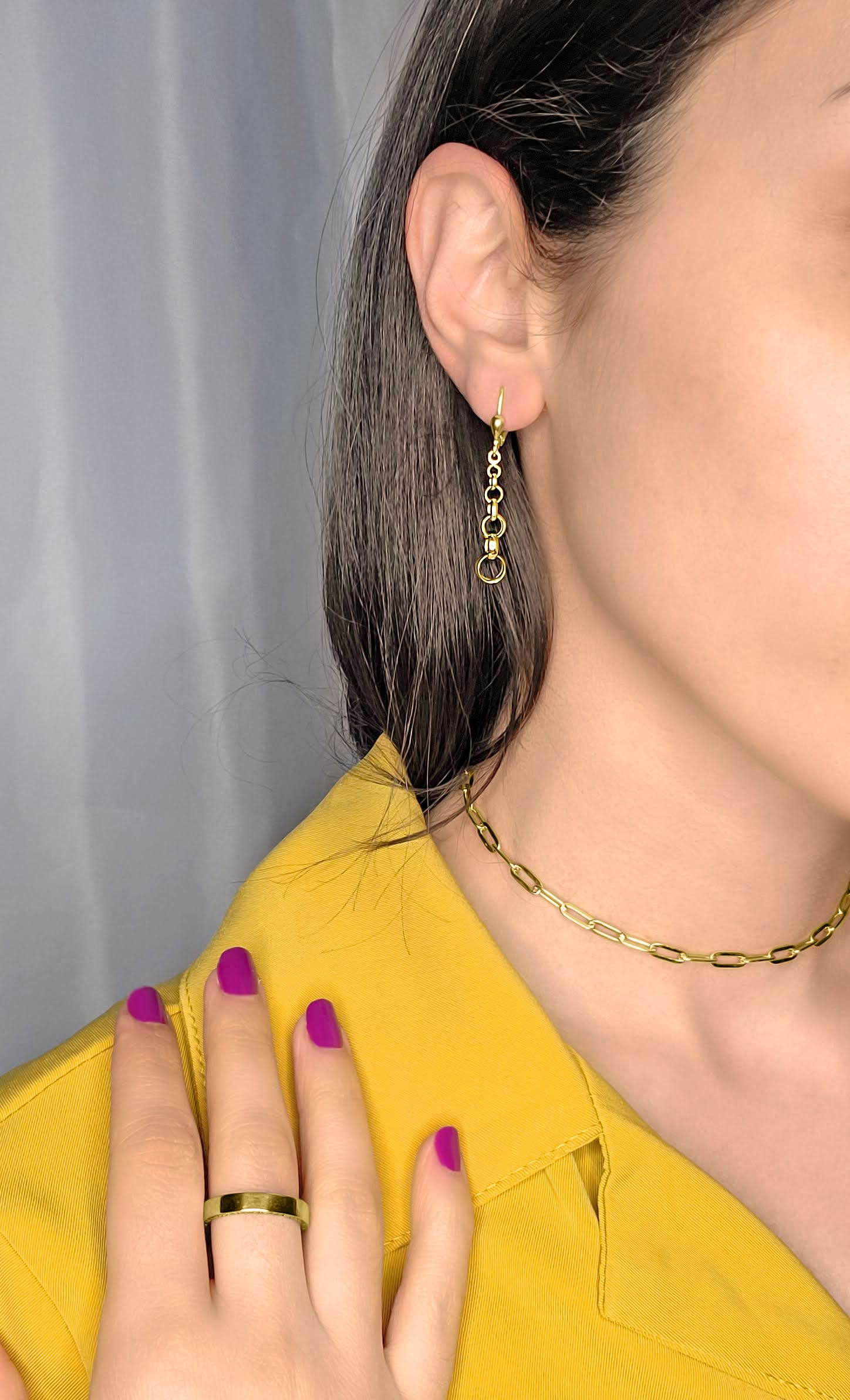 Woman wearing gold rolo drop earrings