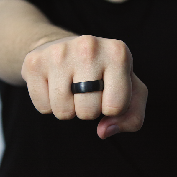 Black Tungsten Carbide Ring with a Brushed Finish and a Rose-Gold Plated Inlay worn by a man 2